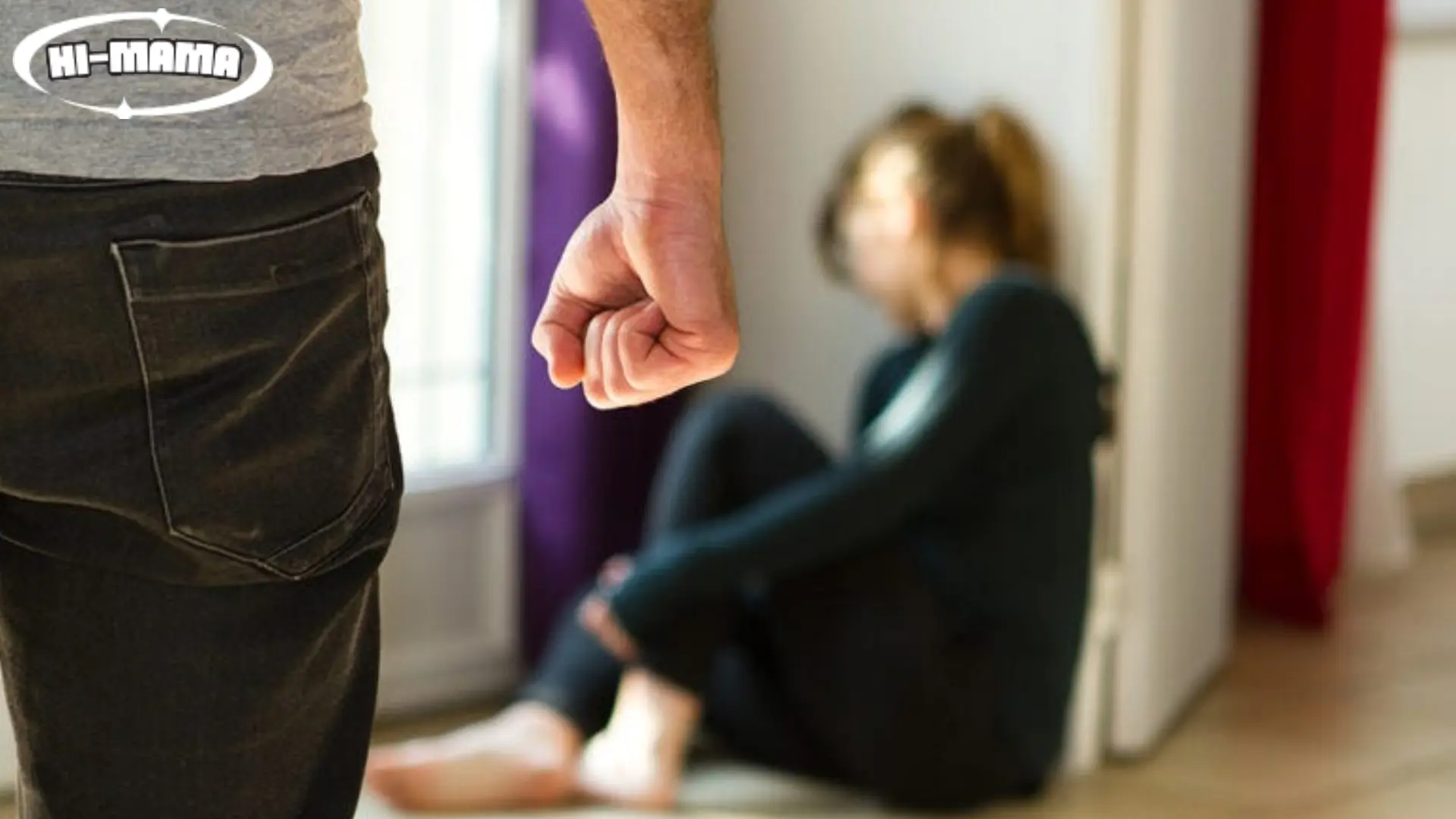 A distressed woman sits on the floor as a man’s clenched fist is visible in the foreground, highlighting the question, 'Is It Illegal to Hit a Girl?