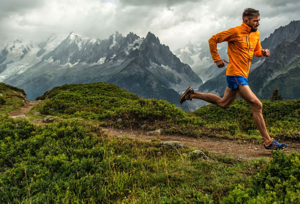 Man wear Orange Hoode and blue knicker Running in Trail Mountains